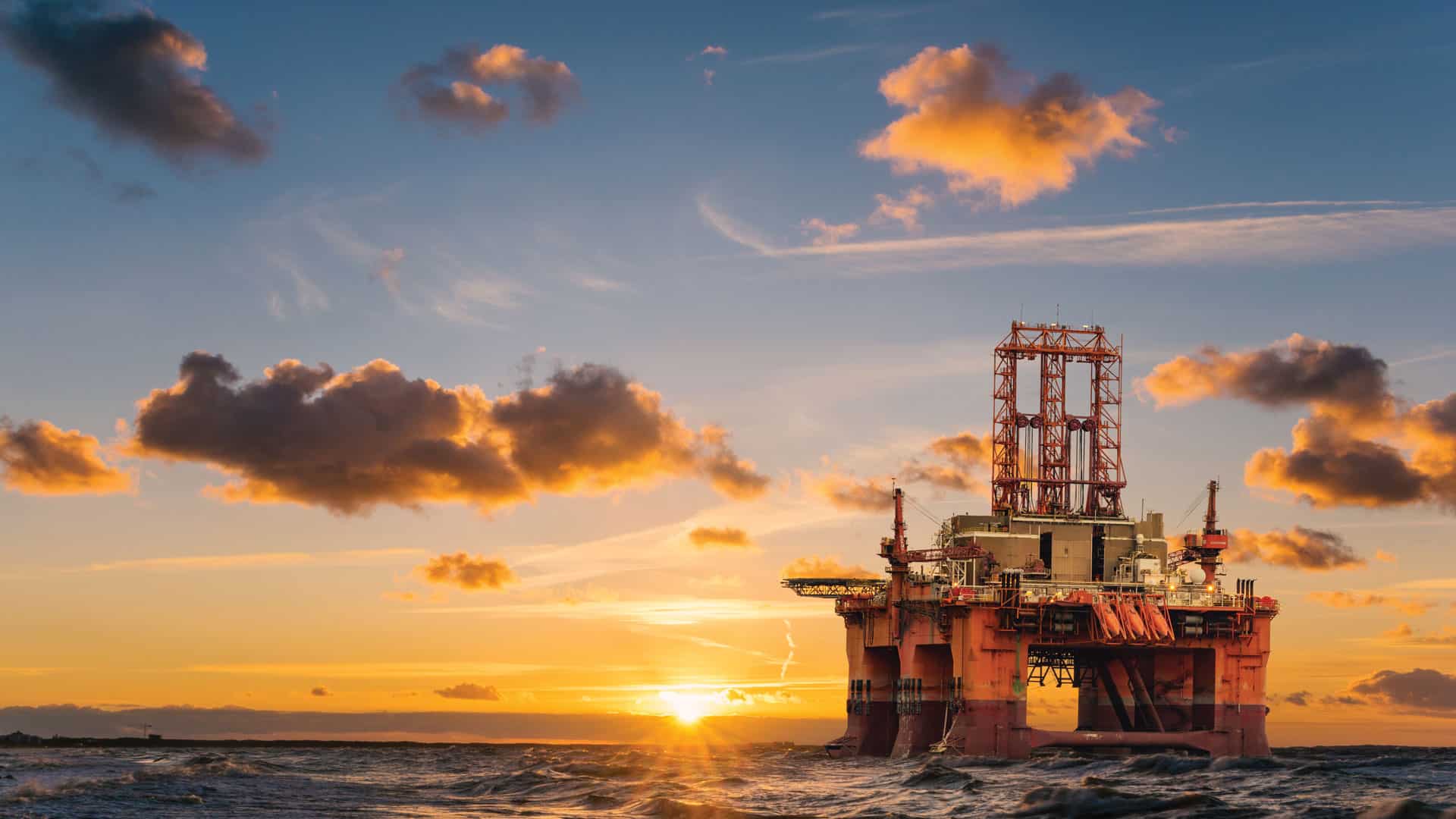 Oil well in middle of ocean at sunset